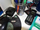 une tasse remplie de stylos, un téléphone portable et une souris posés sur un bureau