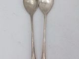 pair of silver spoons on a white surface with a white background