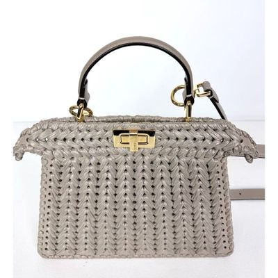 Le petit sac gris est en tissu tissé et possède une poignée en métal.