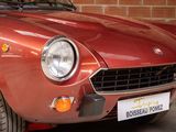 a red car parked in a garage with a brick wall in the background