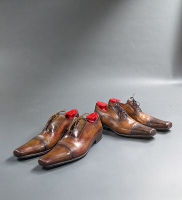 two pairs of brown shoes with red laces sitting on a gray surface