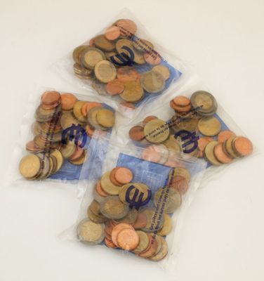 quatre sachets de pièces posés sur une surface blanche