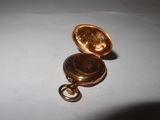 a small gold pocket watch on a white surface