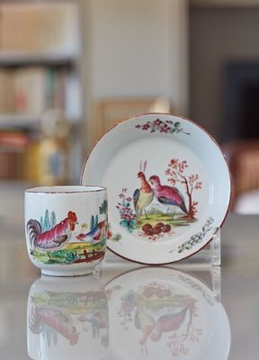 une tasse et une soucoupe posées sur une table devant une bibliothèque