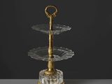un présentoir à gâteaux en verre à trois étages muni d'une poignée dorée