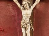 a statue of jesus on a cross on a red wall