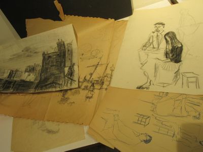 une pile de dessins posée sur une table à côté d'un ordinateur portable
