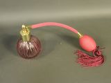 a pink and gold perfume bottle with a pink cord attached
