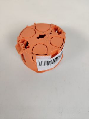 un objet en plastique orange portant un code-barres, posé sur une surface blanche