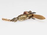 a close up of a gold bug brooch on a white surface
