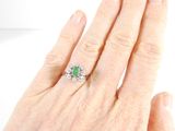 an image of a woman ' s hand holding a ring with a green stone on it