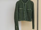 the green jacket is hanging on a hanger in a room