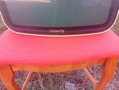 un petit téléviseur posé sur une chaise rouge