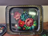 a tray with flowers painted on it sitting on a table
