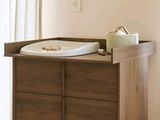 une commode en bois avec un lit de bébé blanc dans un coin