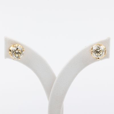 a pair of diamond stud earrings on a stand against a white background