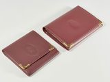 two pink leather wallets sitting on top of a white surface