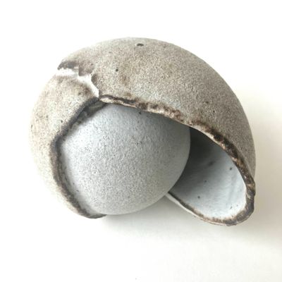 une boule en pierre percée d'un trou, posée sur une surface blanche