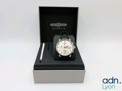 La montre se trouve dans une boîte contenant un stylo et un stylo.