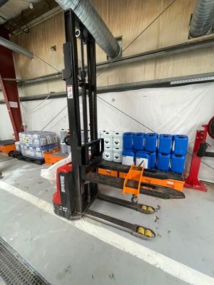 un chariot élévateur transportant plusieurs conteneurs bleus dans un entrepôt