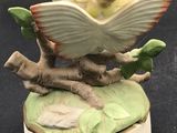 an image of a figurine of a girl reading a book on a tree branch