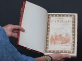 un homme tenant un livre ouvert sur lequel figure une illustration