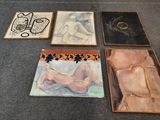 four framed paintings of nudes and a woman on a table