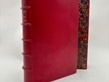 a red book with a red cover sitting on top of a white surface