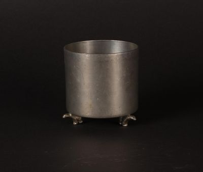 un pot en argent posé sur un socle, sur fond noir