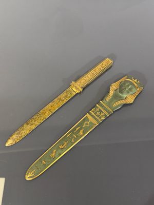 deux objets dorés et verts exposés dans une vitrine