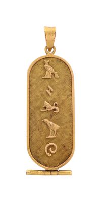 un pendentif plaqué or sur lequel figure une inscription égyptienne