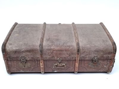 une vieille valise posée sur une surface blanche