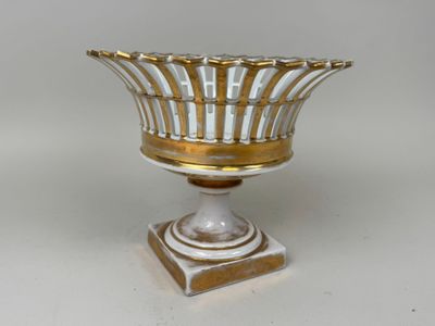 un vase blanc et or sur un support posé sur une table