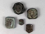 quatre morceaux de métal sur lesquels est représenté un visage, posés sur une surface blanche