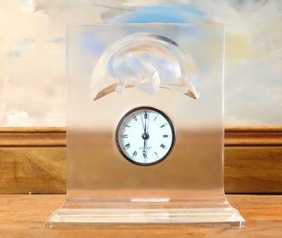 une horloge ornée d'une tête de dauphin, posée sur une table