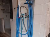 un tuyau bleu fixé au mur à côté des toilettes