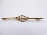 a gold plated tie bar with a flower design on it