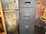 a filing cabinet in the corner of a room next to a table