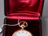 a small gold pocket watch in a red case