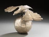 a silver vase with a bird on top of it