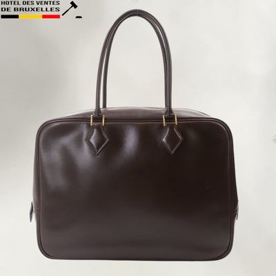 Le sac à main en cuir marron est posé sur une surface blanche.