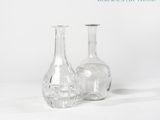 deux vases en verre posés l'un à côté de l'autre sur une surface blanche