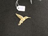 a gold hummingbird brooch with a tag on it