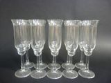 six clear wine glasses are lined up on a black surface