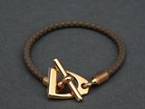a close up of a brown leather bracelet with a gold clasp