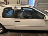 a white car parked in a garage with its door open