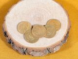 three coins sitting on a piece of wood on a yellow background