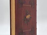 an old book with a floral design on it sitting on a white surface