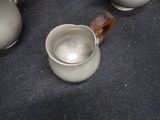 a silver pitcher sitting on the floor next to a pair of silver vases