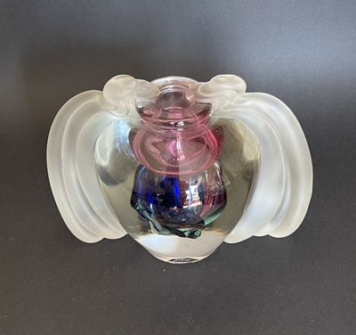 a glass vase with a pink and blue candle inside of it